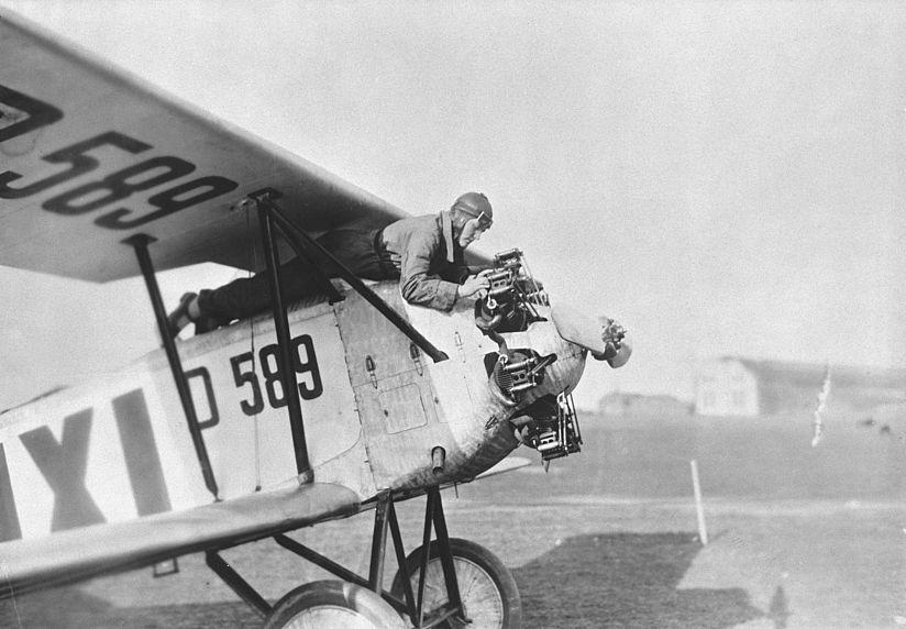LRD_Dietrich-Gobiet_Bussard_Archiv_R_1880-09.jpg Die Pilotin liegt auf dem Dach ihres parkenden Flugzeugs und kontrolliert den Motor.